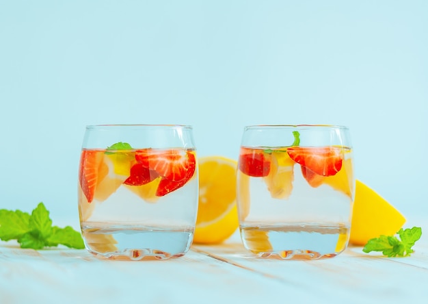 Twee glazen met een verfrissend zomerdrankje gemaakt van citroen, aardbei en munt. limonade water. cocktail van citrus en bessen.