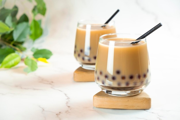 Twee glazen met melk bubble tea met heerlijke tapioca parels groene bladeren op marmeren achtergrond Beroemde Taiwan milk jelly tea Trendy drankjes met kopie ruimte