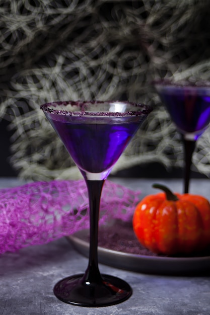 Twee glazen met paarse cocktail voor Halloween-feest op donker