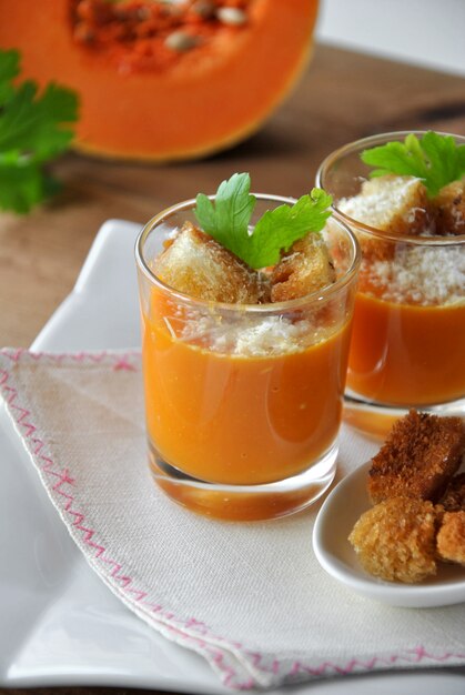 Twee glazen met pompoensoep en brood en parmezaanse kaas