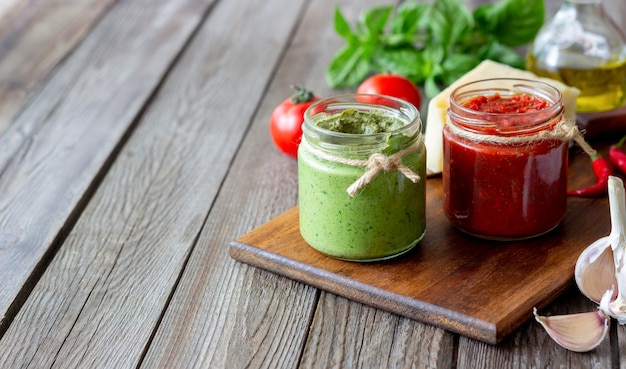 Twee glazen potten met rode pesto en basilicumpesto. Nationale keuken. Gezond eten. Vegetarisch eten.