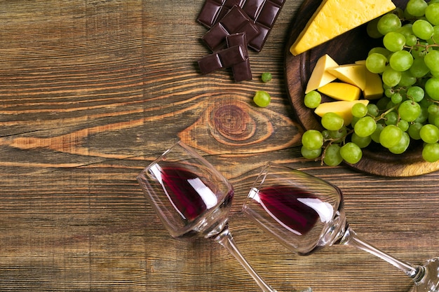 Twee glazen rode wijn, kaas, groene druiven en chocolade, bovenaanzicht. Ruimte kopiëren. Stilleven. plat leggen