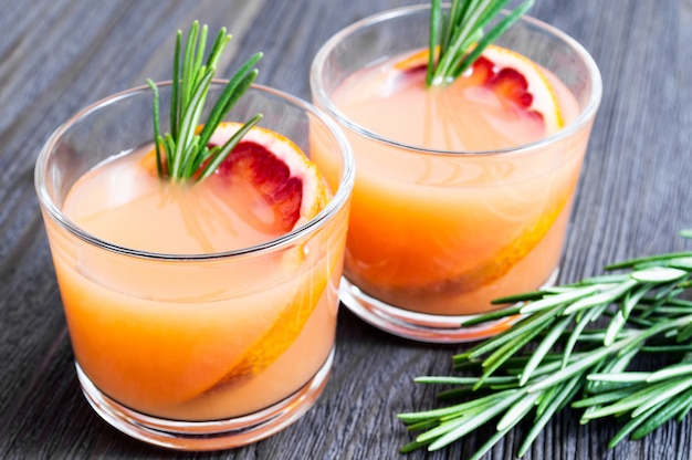 Twee glazen verse de zomerdrank met bloedsinaasappel en rozemarijn op een donkere houten achtergrond