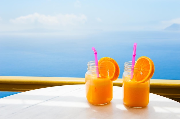 Twee glazen verse jus d'orange op tafel met uitzicht op de zee.
