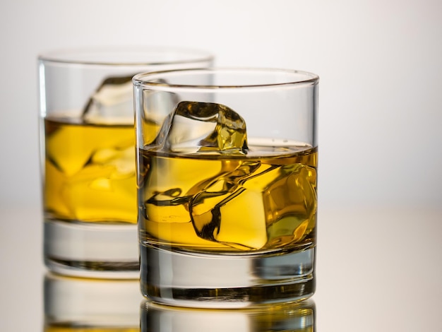 Twee glazen whisky on the rocks op een reflecterend oppervlak