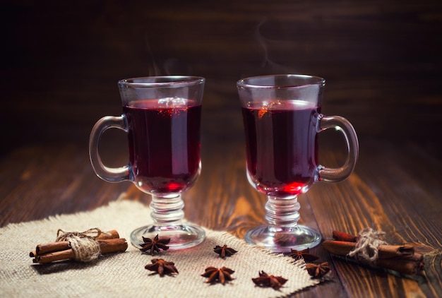 Twee glazen winterverwarmende rode warme drank Kerst glühwein op houten achtergrond met spice-orange sliceanise en kaneelstokjes