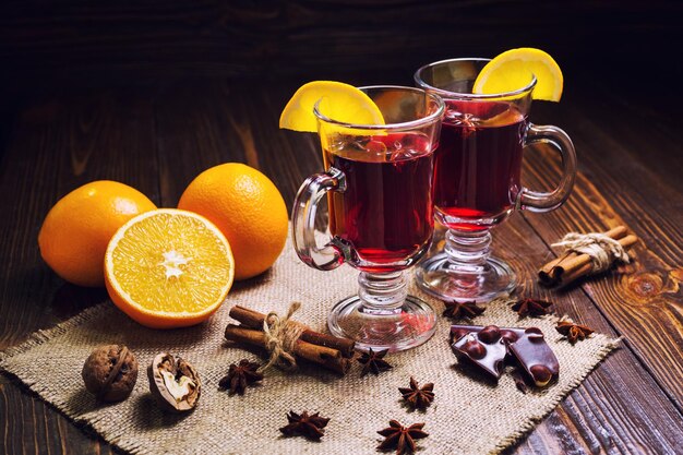 Twee glazen winterverwarmende rode warme drank Kerst glühwein op houten achtergrond met spice-orange sliceanise en kaneelstokjes