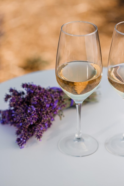 Twee glazen witte wijn in een lavendelveld in Provance Violette bloemen op de achtergrond