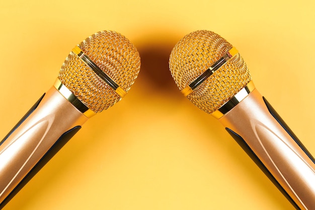 Twee gouden microfoons geïsoleerd op gele achtergrond close-up
