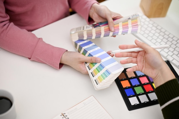 Twee grafische ontwerpers ontwerpen samen hun nieuwe product en kiezen kleur uit de kleurenkaart