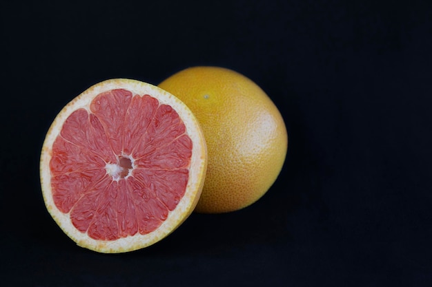 Twee grapefruits tegen zwarte achtergrond met exemplaarruimte