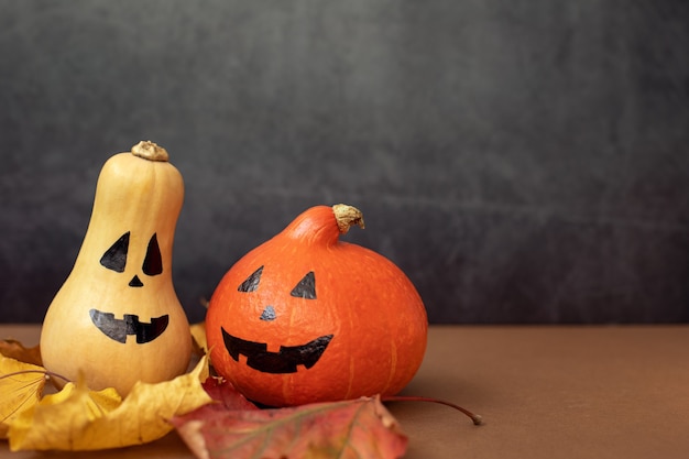 Twee grappige Halloween-pompoenen met geschilderde gezichten Donkergrijze achtergrond Themafeestconcept