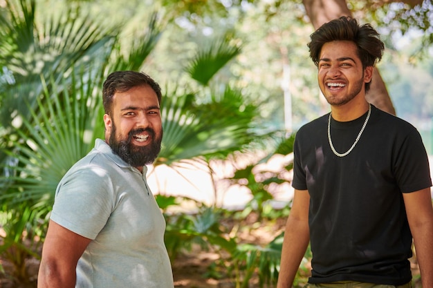 Twee grappige indiase mannen lachen en spreken Hindi op de achtergrond van groene palmbladeren in het openbare park