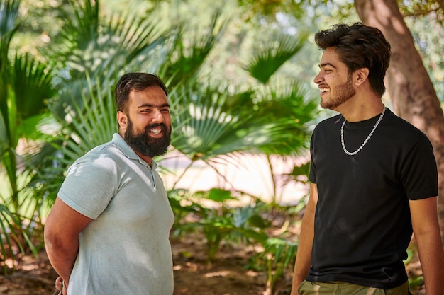 Twee grappige indiase mannen lachen en spreken Hindi op de achtergrond van groene palmbladeren in het openbare park