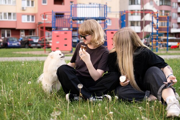 Twee grappige meisjes eten ijs en spelen met een Pommeren hond