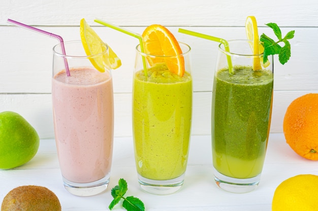 Twee groene en roze fruit smoothies in glazen bekers met rietjes op een witte achtergrond. Horizontale oriëntatie Foto van hoge kwaliteit