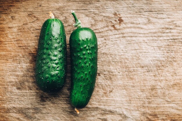 Twee groene komkommers op een houten tafel achtergrond. Bovenaanzicht. Kopiëren, lege ruimte voor tekst