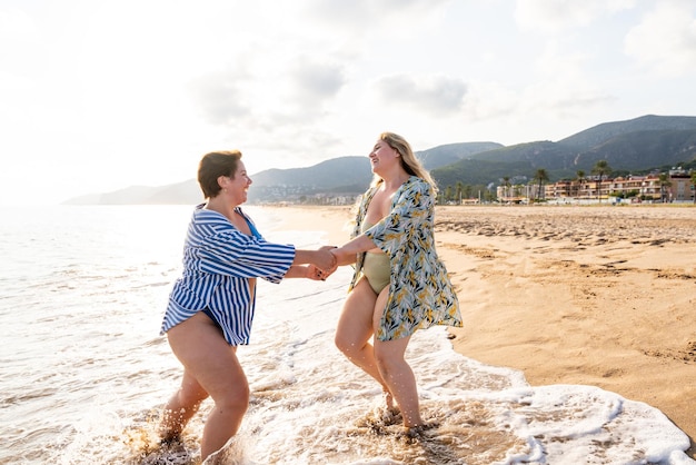 Twee grote maten vrouwen met badkleding op het strand