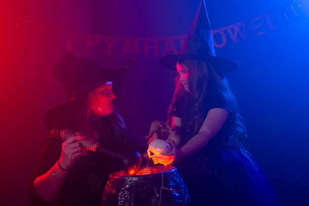 Twee Halloween-heksen die een drankje maken en in Halloween-nacht toveren. Magie, vakantie en mystiek concept.