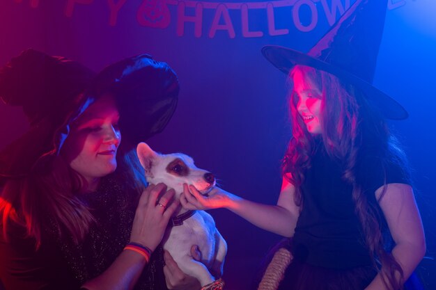 Twee halloween-heksen die magie maken met hond jack russell terrier in halloween-nacht. magie, vakantie en mystiek concept.