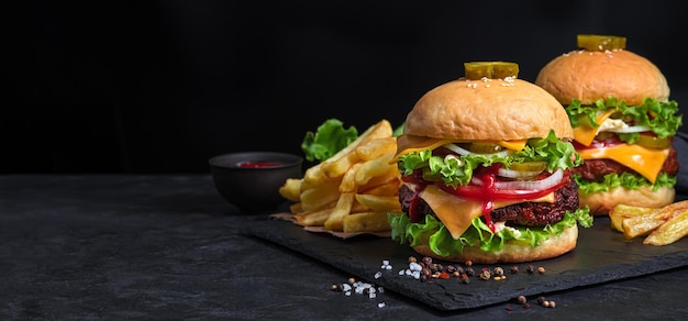 Twee hamburgers, frietjes en sap op een zwarte achtergrond