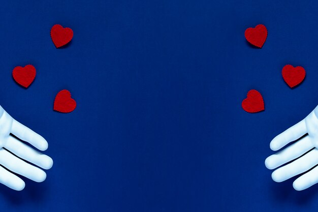 Twee handen gooien rode harten op een blauwe achtergrond. Het concept voor Valentijnsdag