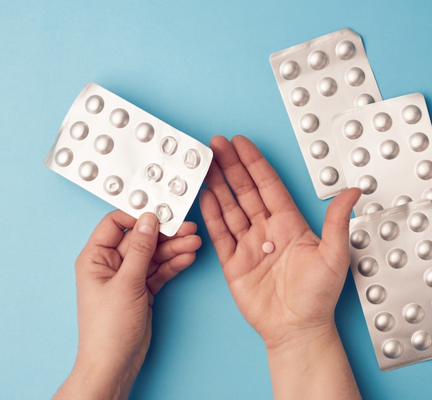 Twee handen houden een pakket ronde tabletten in blisterverpakkingen vast