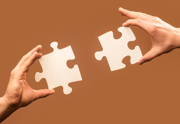 Twee handen proberen te verbinden paar puzzelstukje op grijze achtergrond Teamwork concept Closeup hand van aansluiten puzzel Holding puzzel Business oplossingen succes en strategie concept