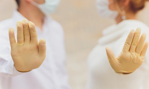 Twee handen van een paar in plastic handschoenen houden elkaar.