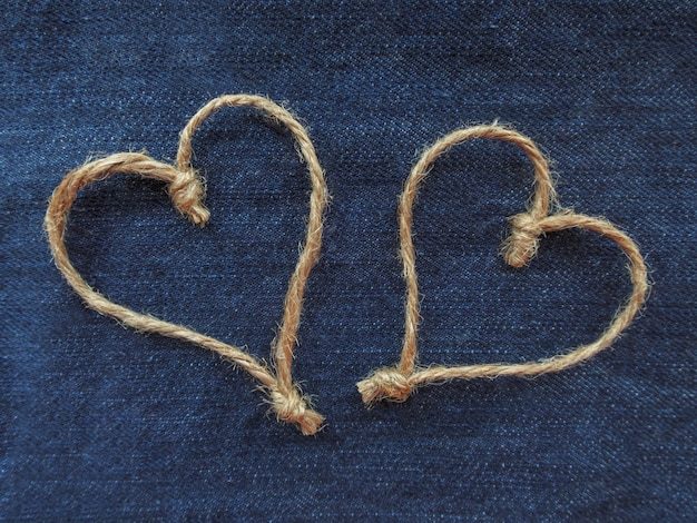 Foto twee hartenteken gemaakt van touw op blauw denim. wereldhartdag of liefdeconcept. detailopname