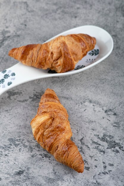 Twee heerlijke verse croissantgebakjes op stenen oppervlak.