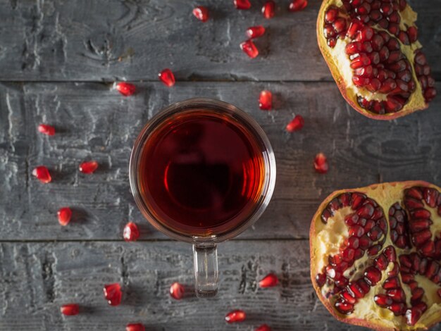 Twee helften van rijpe granaatappel en granaatappelsap op een houten tafel. Drink nuttig voor de gezondheid. Plat leggen.