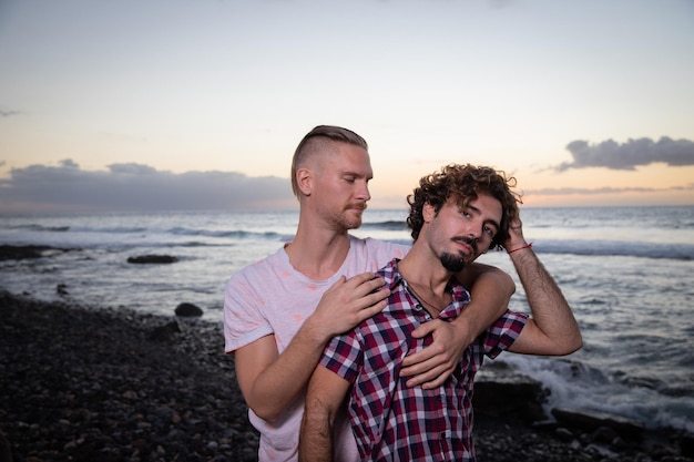 Twee homoseksuele geliefden omhelzen elkaar op het strand tijdens zonsondergang op vakantie