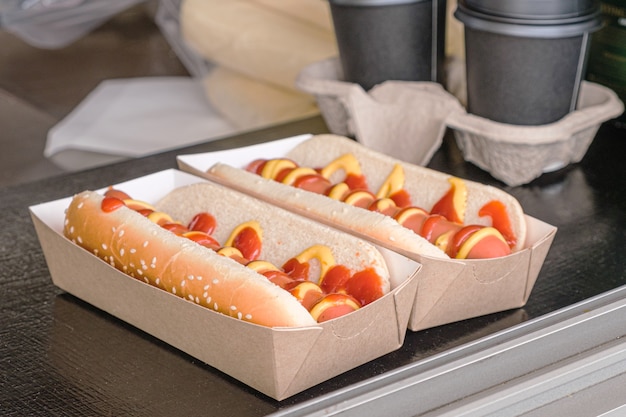 Twee hotdogs in een kartonnen doos op de toonbank van een meeneemkar voor straatvoedsel.