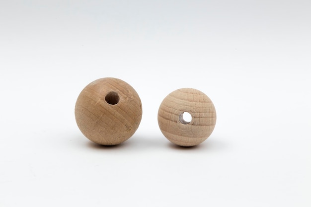 Twee houten ballen van verschillende grootte die een gat in het midden hebben en kunnen worden gebruikt voor een ketting