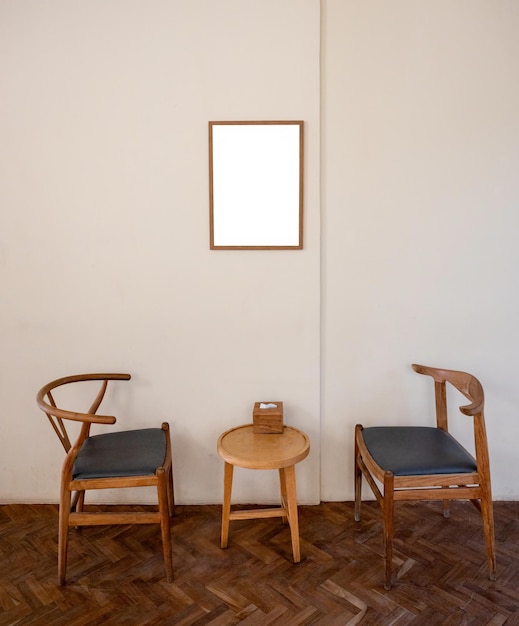 Twee houten fauteuil met tafel en lege fotolijst in woonkamer