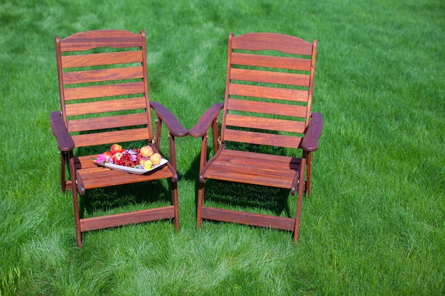 Twee houten stoelen op het gras met vaas met bloemen