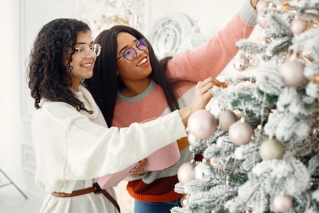 Twee Indiase meisjes in brillen die de kerstboom versieren