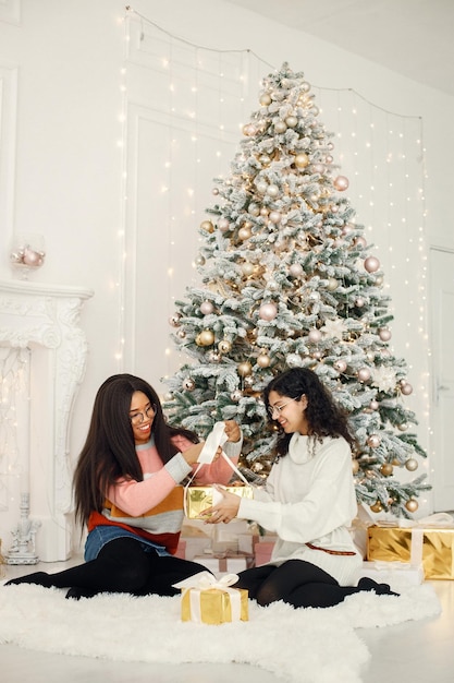 Twee Indiase meisjes met een bril die bij de kerstboom zitten