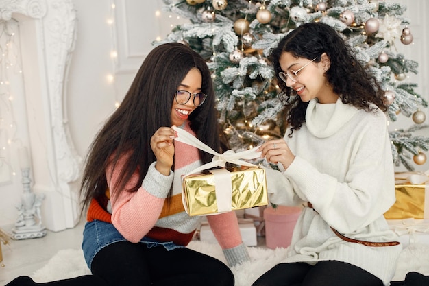 Twee Indiase meisjes met een bril die bij de kerstboom zitten