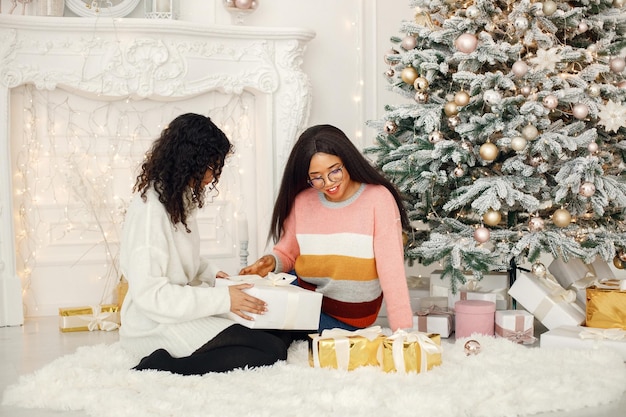 Twee Indiase meisjes met een bril die bij de kerstboom zitten