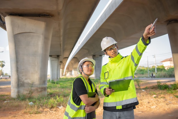 Twee ingenieurs bespreken over werk op de plaats van een grote brug in aanbouw Management consulting mensen discussie met ingenieurs over de voortgang en bouwplanning van de snelweg