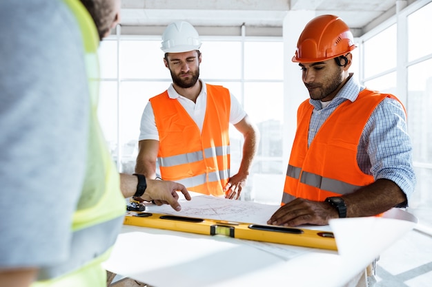 Twee ingenieurs man kijken naar projectplan op de tafel op de bouwplaats