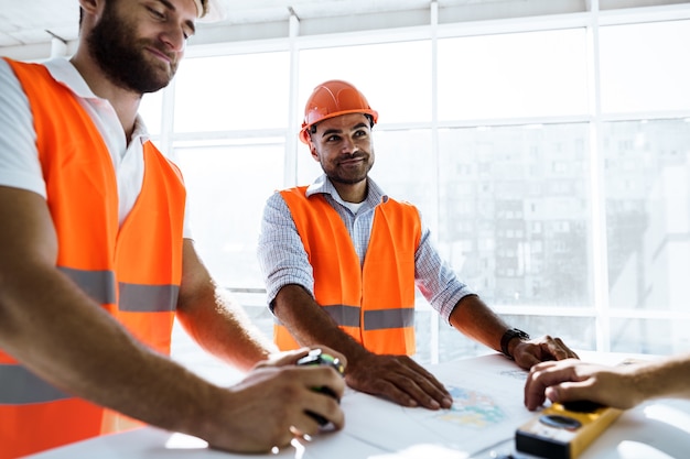 Twee ingenieurs man kijken naar projectplan op de tafel op de bouwplaats