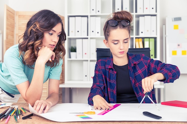 Twee ingenieurs werken aan blauwdruk met kompas