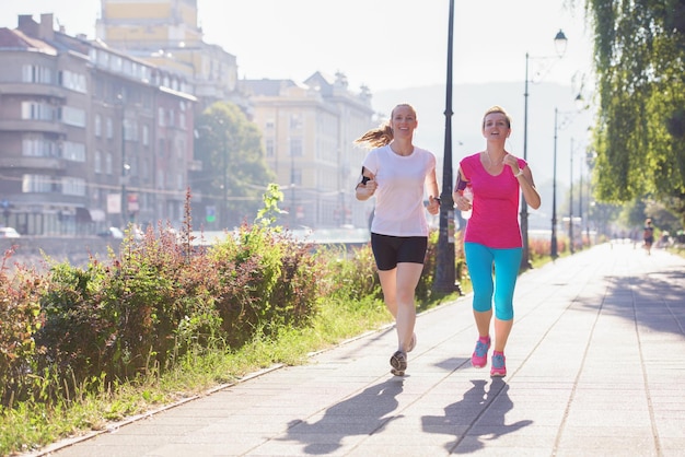 twee joggende vriendinnen van middelbare leeftijd hebben ochtendtraining met zonsopgang op de achtergrond