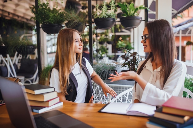 Twee jonge aantrekkelijke bloggers zitten in café en praten