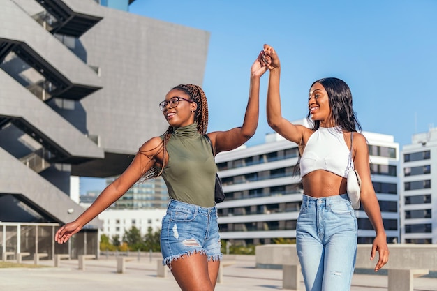 Twee jonge Afrikaanse vrienden dansen in de stad, hand in hand, concept van vriendschap en stedelijke levensstijl