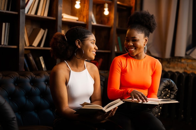 twee jonge Afrikaanse vrouwen die boeken in de bibliotheek lezen