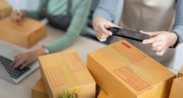 Twee jonge Aziatische vrouwelijke ondernemers bereiden een pakketdoos voor en controleren online bestellingen van producten voor levering aan de klant verpakking Shopping Online concept